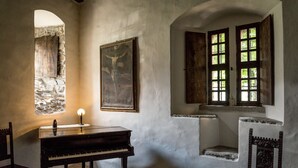 Una habitación con un piano, un cuadro y una ventana de varios paneles.