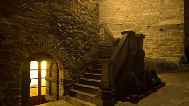 Una escalera de piedra que conduce a un nivel superior, con una puerta de madera al final.