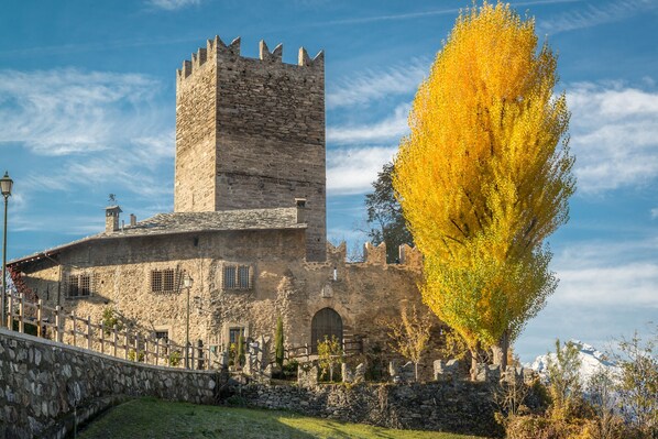 A historic stone building with a tall tower, a stone wall, and a wooden fence.