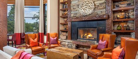 A modern living room with leather armchairs, a fireplace, and a stone wall.