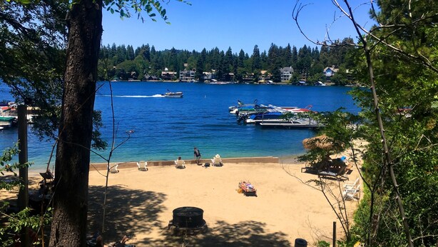 A beach with boats, a clear blue sky, and a forested area. - Lake Arrowhead Resort and Spa (Lake Arrowhead)