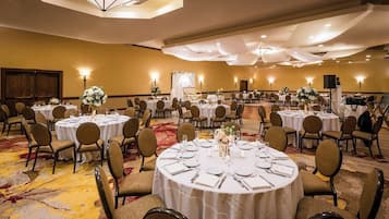 A banquet hall with round tables set for dining, chairs, and tables with white tablecloths.