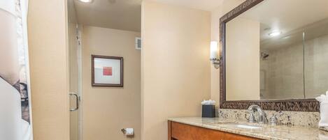A hotel bathroom with a shower, a sink with a mirror, and a towel rack.