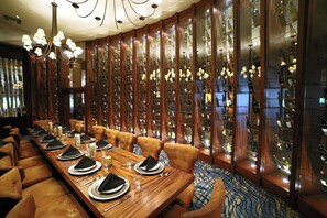 A formal dining room with a long table set for a meal, surrounded by tall wooden cabinets displaying wine bottles. - Lake Arrowhead Resort and Spa (Lake Arrowhead)