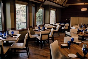A restaurant with multiple tables and chairs, large windows, and a wooden ceiling. - Lake Arrowhead Resort and Spa (Lake Arrowhead)