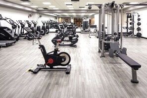 Un gimnasio con varias máquinas de ejercicio, incluyendo cintas de correr y equipo de levantamiento de pesas.