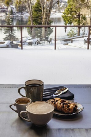 A table with a coffee cup, a mug, and a pastry on a balcony overlooking a snowy landscape. - Lake Arrowhead Resort and Spa (Lake Arrowhead)