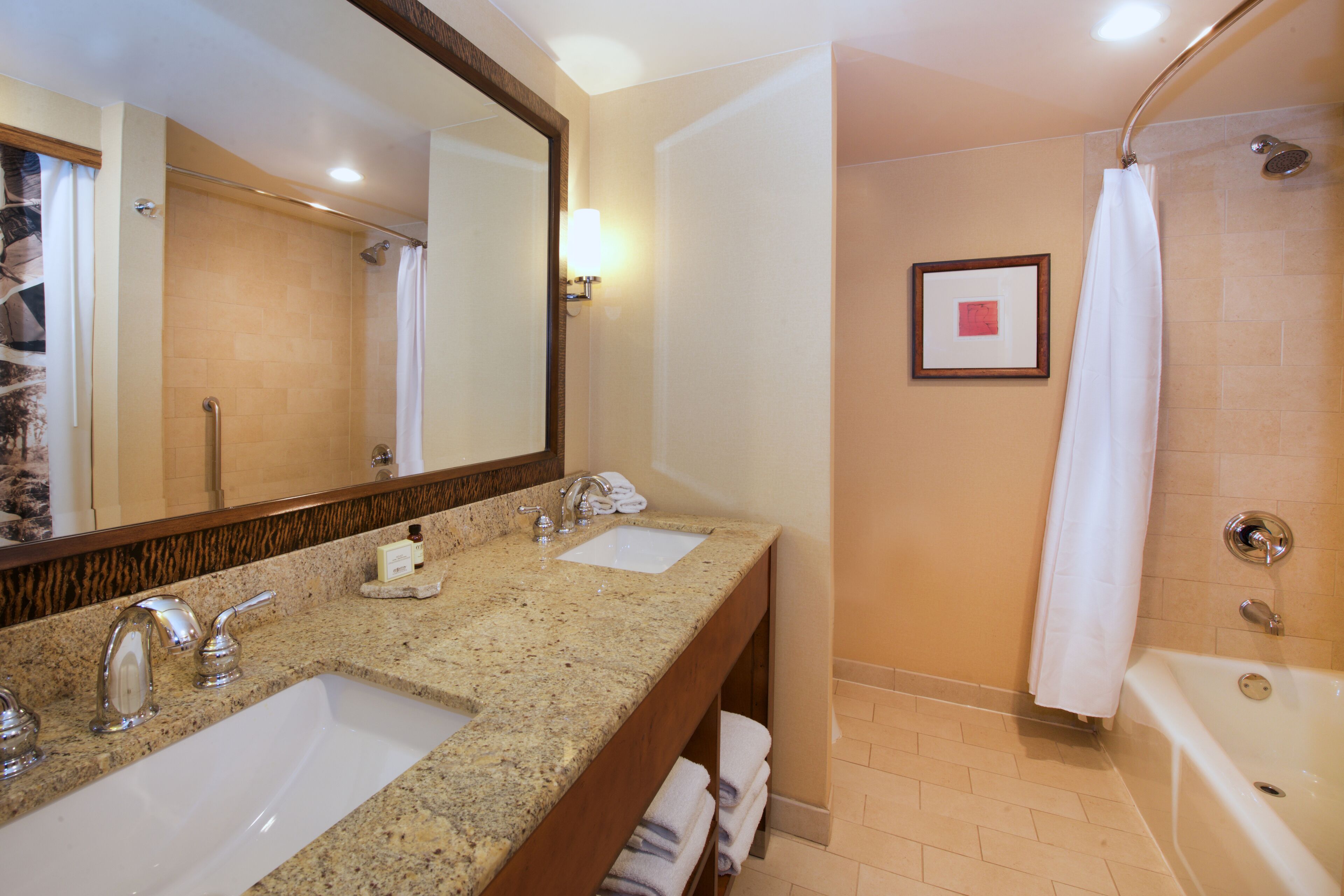 Une salle de bain avec deux lavabos, un grand miroir, une douche et une baignoire.