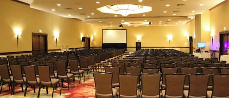 A conference room with rows of chairs, a projector screen, and a large chandelier.