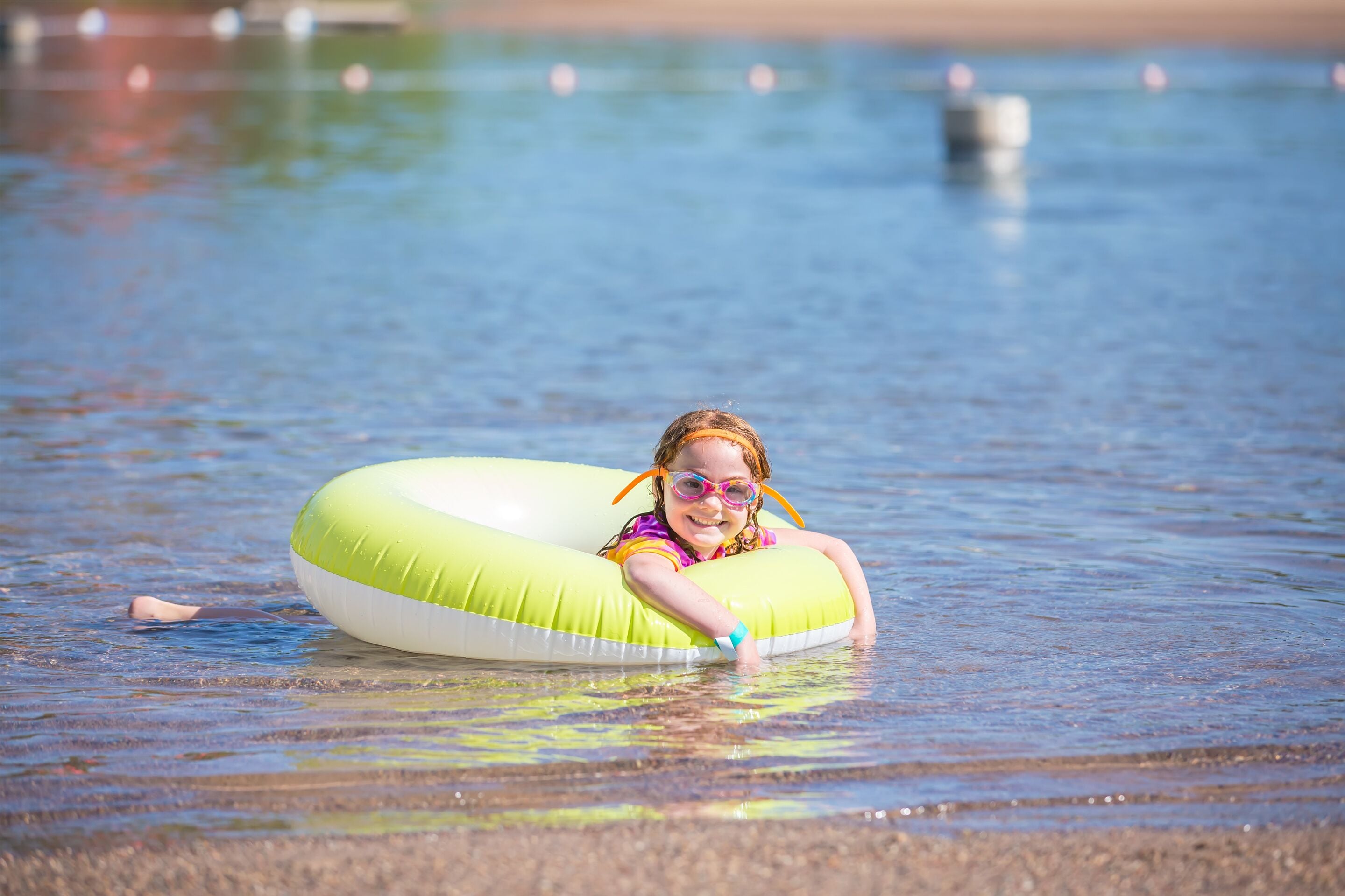 A person in a green inflatable ring in shallow water.