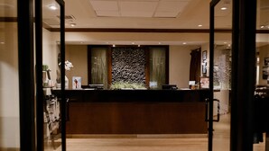 A reception area with a wooden reception desk, a stone wall, and a plant in the center. - Lake Arrowhead Resort and Spa (Lake Arrowhead)