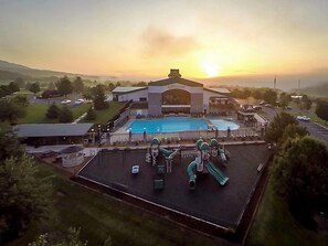 Une piscine avec un toboggan, entourée d’une clôture, et un bâtiment sur lequel est apposée une enseigne indiquant « CENTRE TOURISTIQUE ».