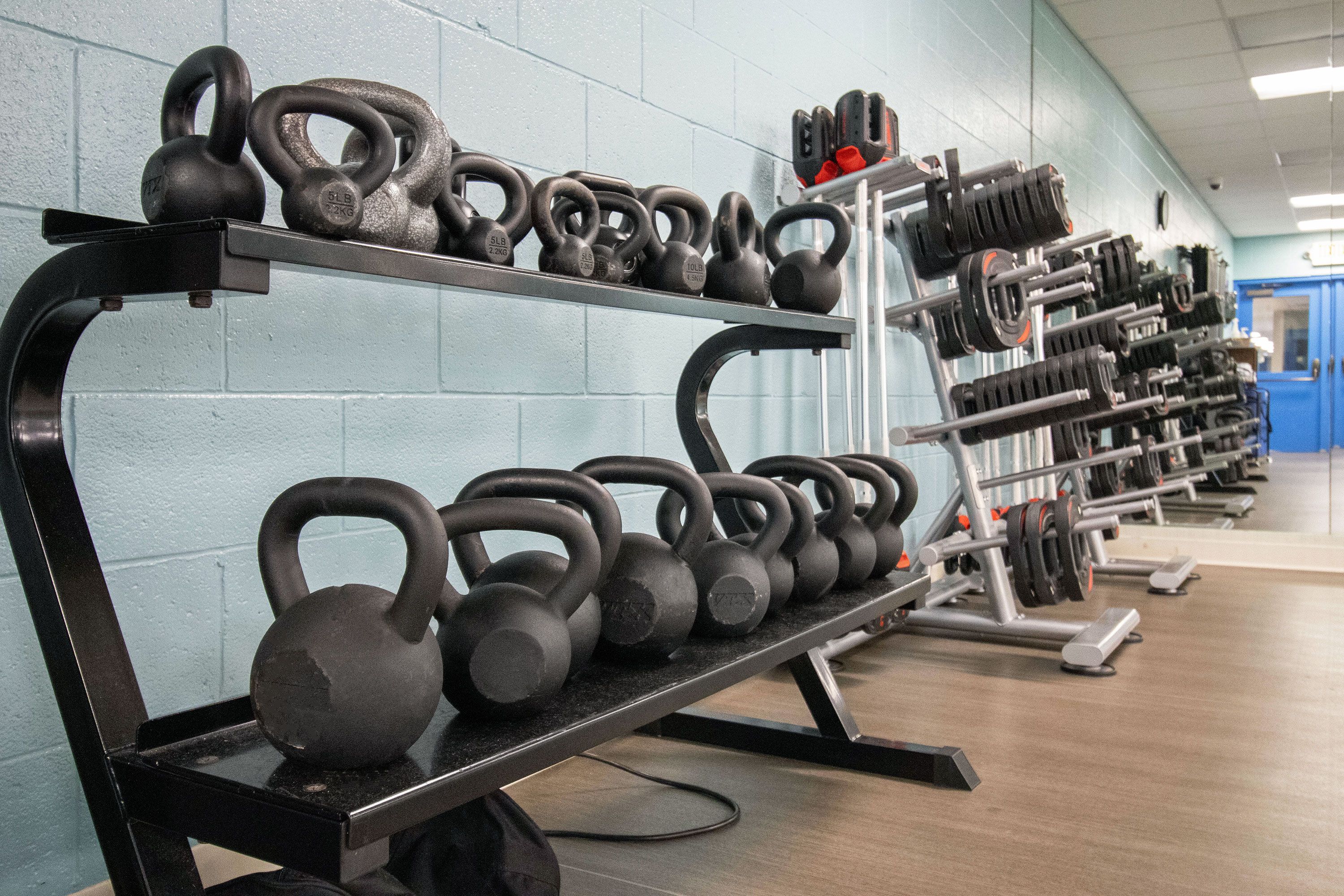 Ett gym med kettlebells och hantlar på ställ.