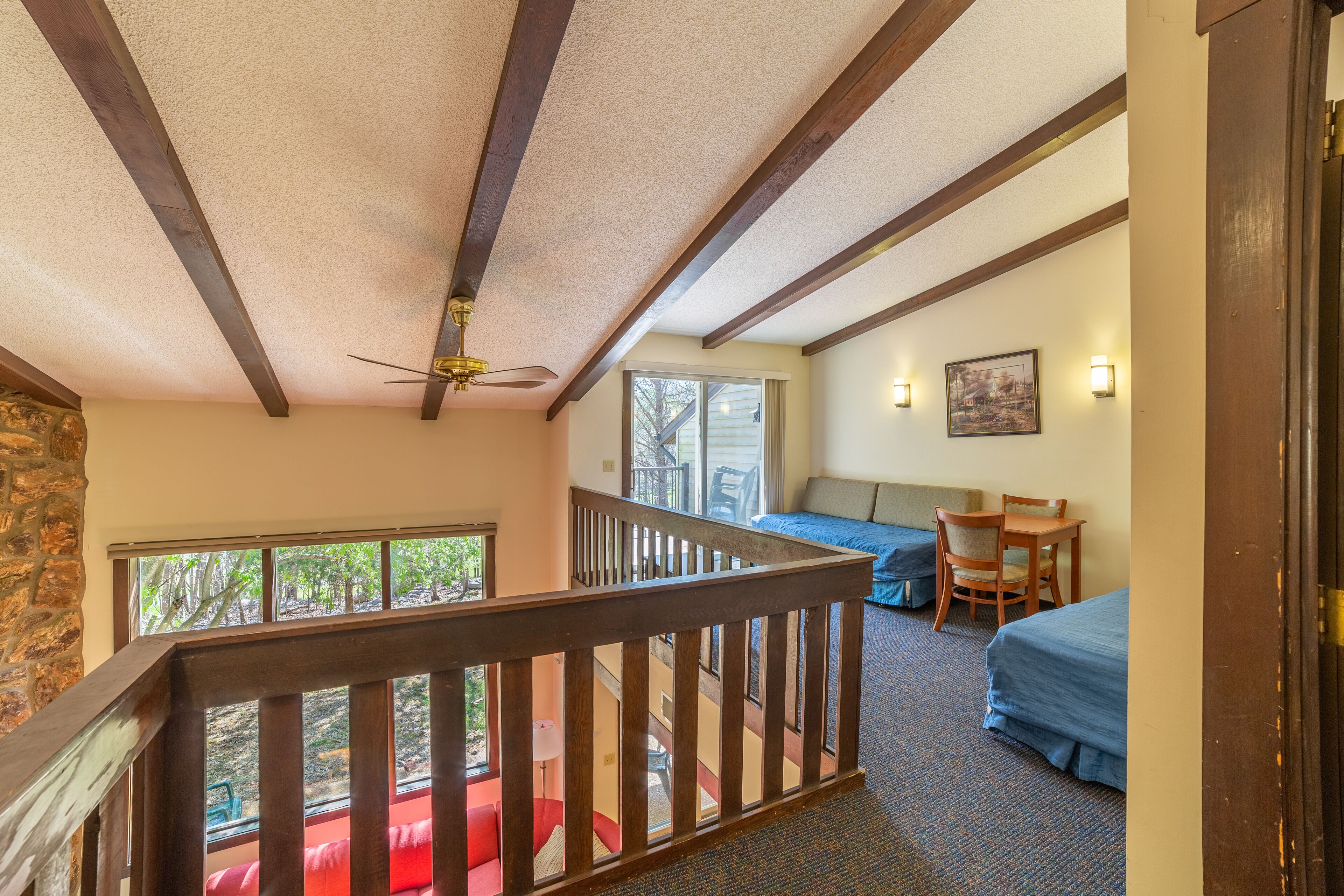 A room with a wooden ceiling, a bed, a desk, and a chair.
