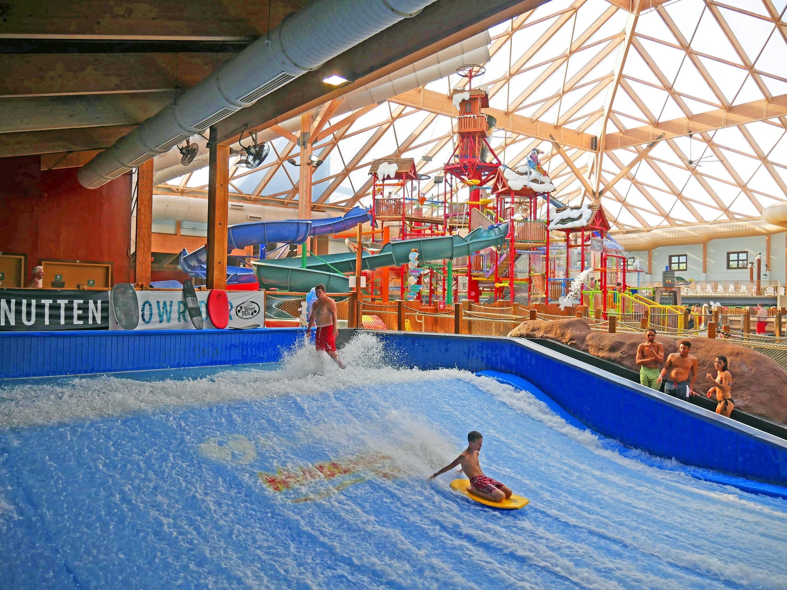 An indoor water park with a wave pool, slides, and a wooden structure.