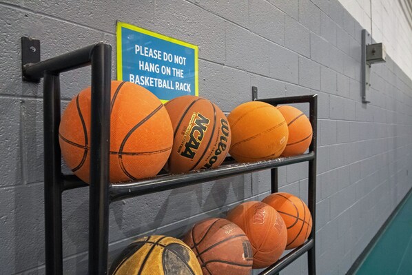 Un présentoir contenant plusieurs ballons de basket appuyés contre un mur.