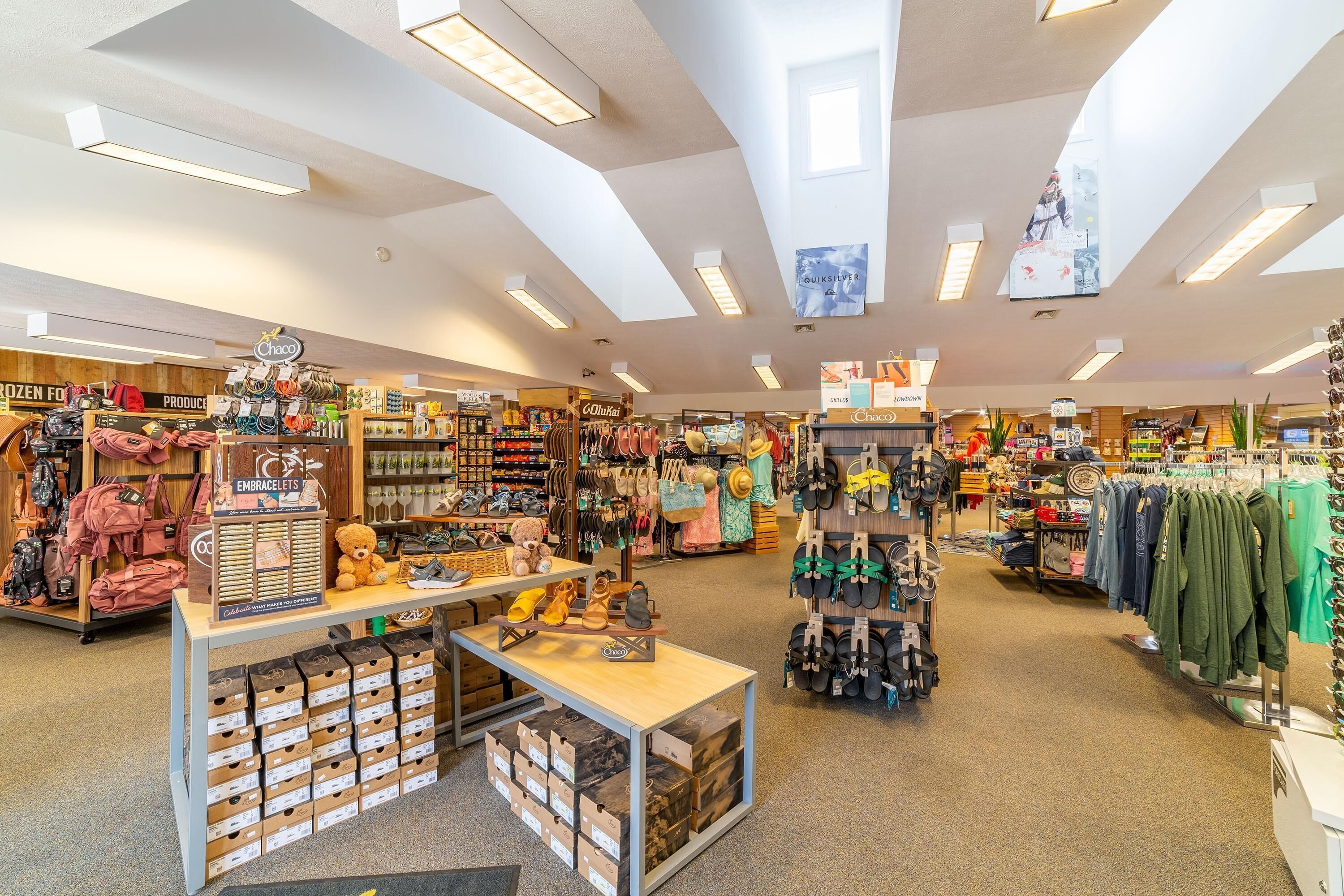 A well-lit retail store with various clothing and accessories on display, including backpacks, shoes, and handbags.