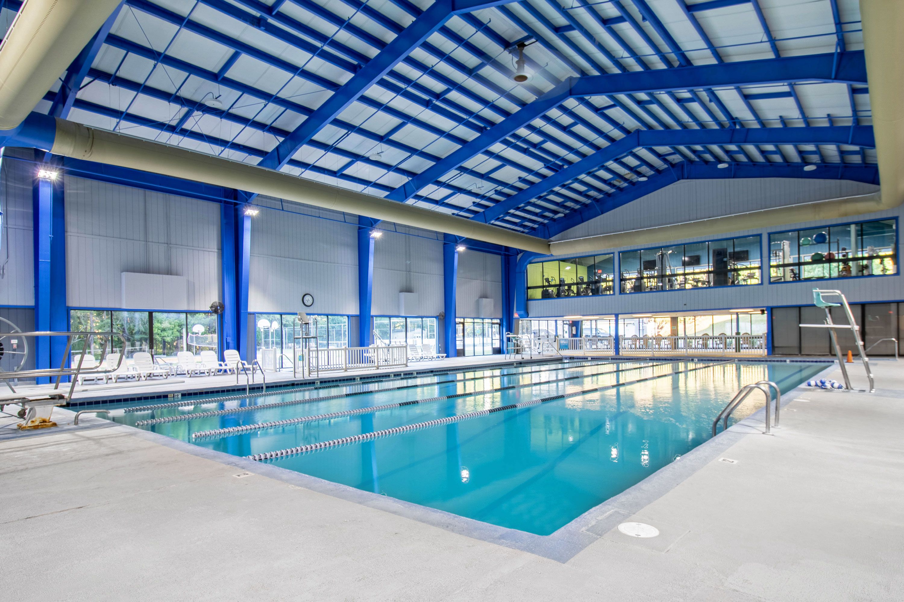 Una piscina interior con carriles delimitados, un trampolín y una zona de espectadores en un segundo nivel.