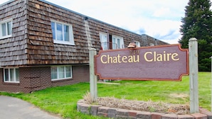 Señal de Chateau Claire, un edificio con fachada de ladrillo y revestimiento de madera.