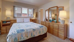 Un dormitorio con una cama grande, cómoda de madera, lámparas de noche y una ventana con persianas.