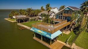 A waterfront property with a pool, wooden deck, and multiple buildings.