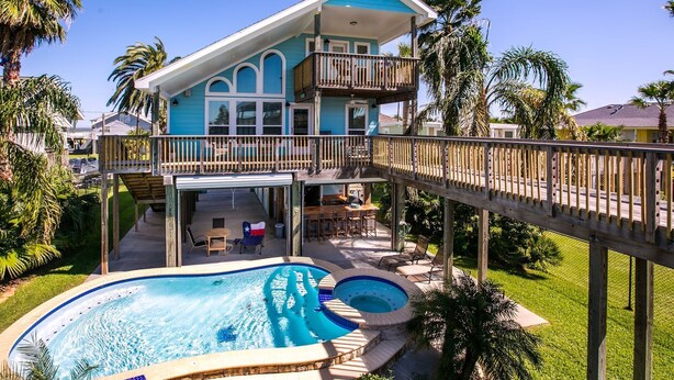 A two-story house with a balcony, a swimming pool, and a deck.