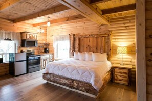 L’intérieur d’une cabane en rondins comprend un lit en bois, un coin cuisine et un espace repas.