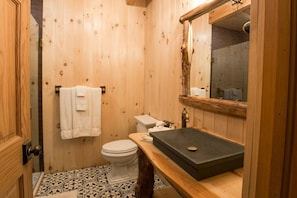 Ein Badezimmer mit Holzpaneelen, einem Waschbecken, einer Toilette und einem Spiegel über dem Waschbecken.