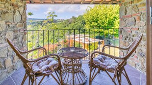 Ein Balkon mit Korbmöbeln und Blick auf eine grüne Landschaft.
