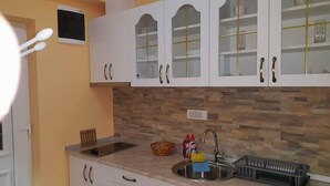 A kitchen with white cabinets, a stone backsplash, a sink, and a toaster. - Akva Gold Apartmani (Arandelovac)