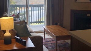 Una sala de estar con sofá, lámpara, mesa de madera y chimenea.