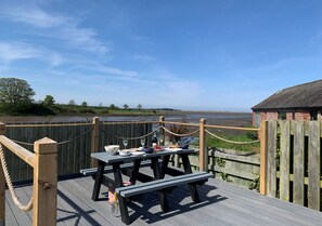 Enjoy a casual dining experience on this deck overlooking a serene body of water.
