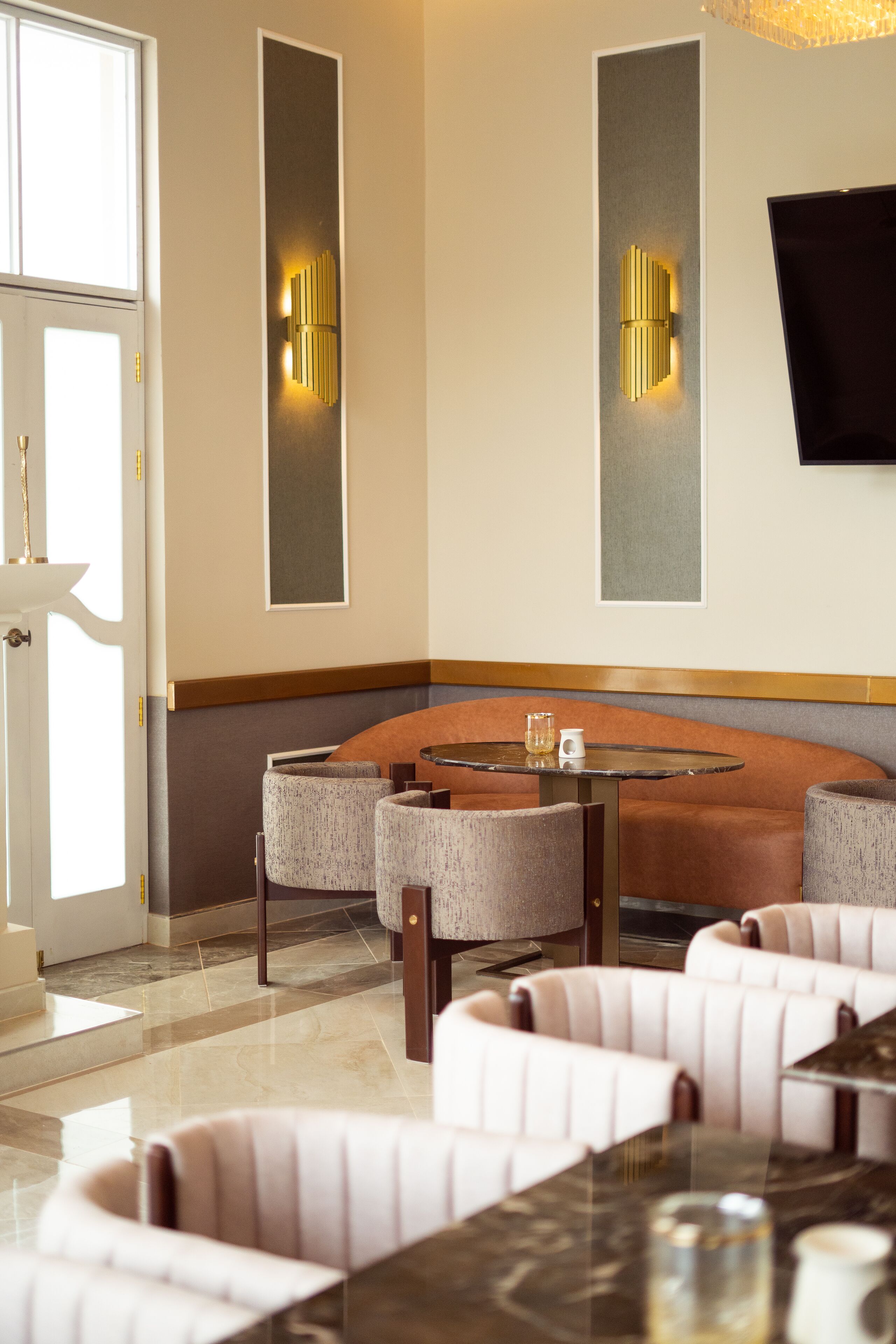 A modern interior with a round table, cushioned seating, and wall-mounted lighting.