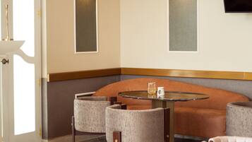 A modern interior with a round table, cushioned seating, and wall-mounted lighting.
