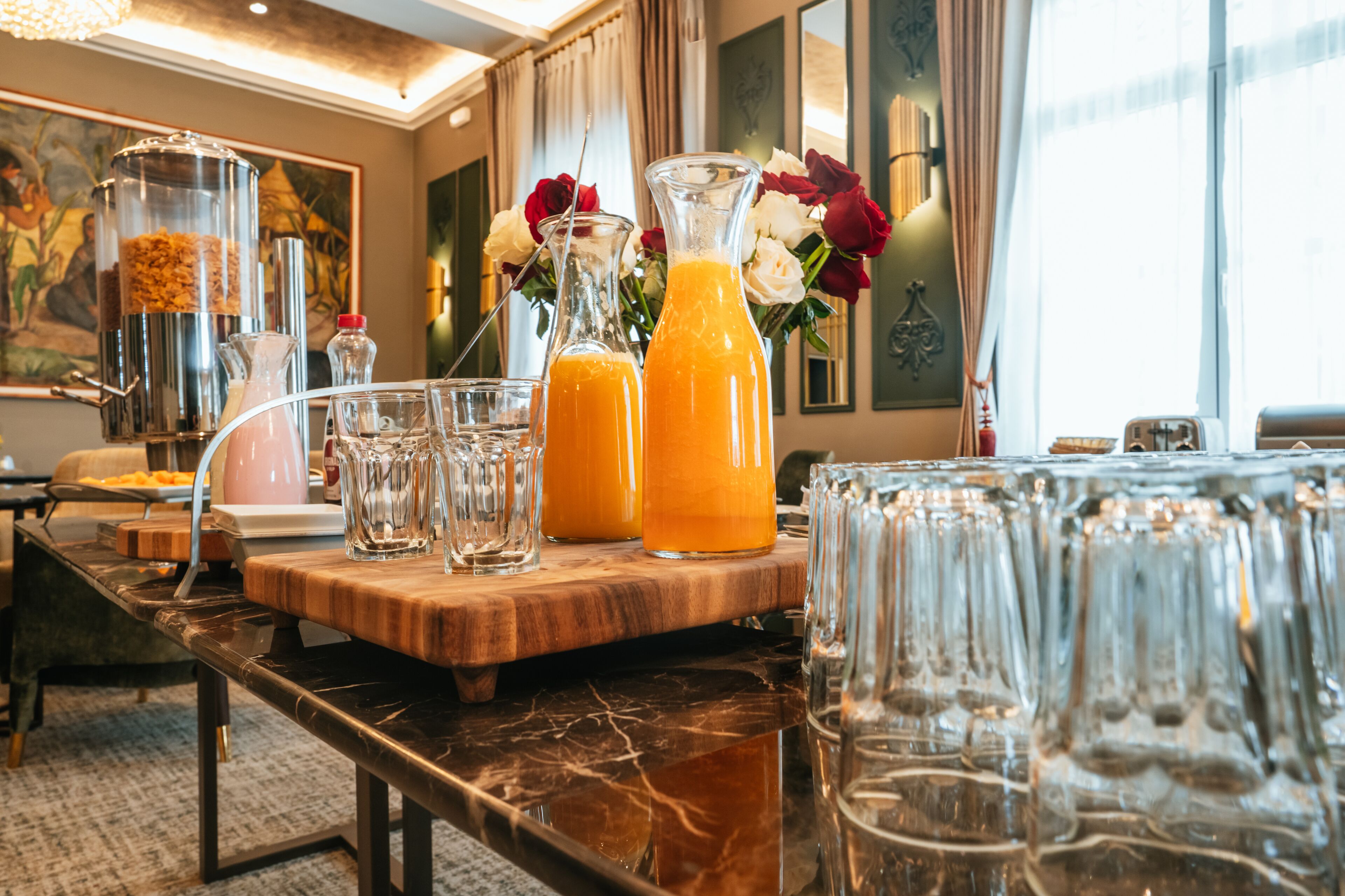 A breakfast bar with a marble countertop, clear glasses, and orange juice bottles.