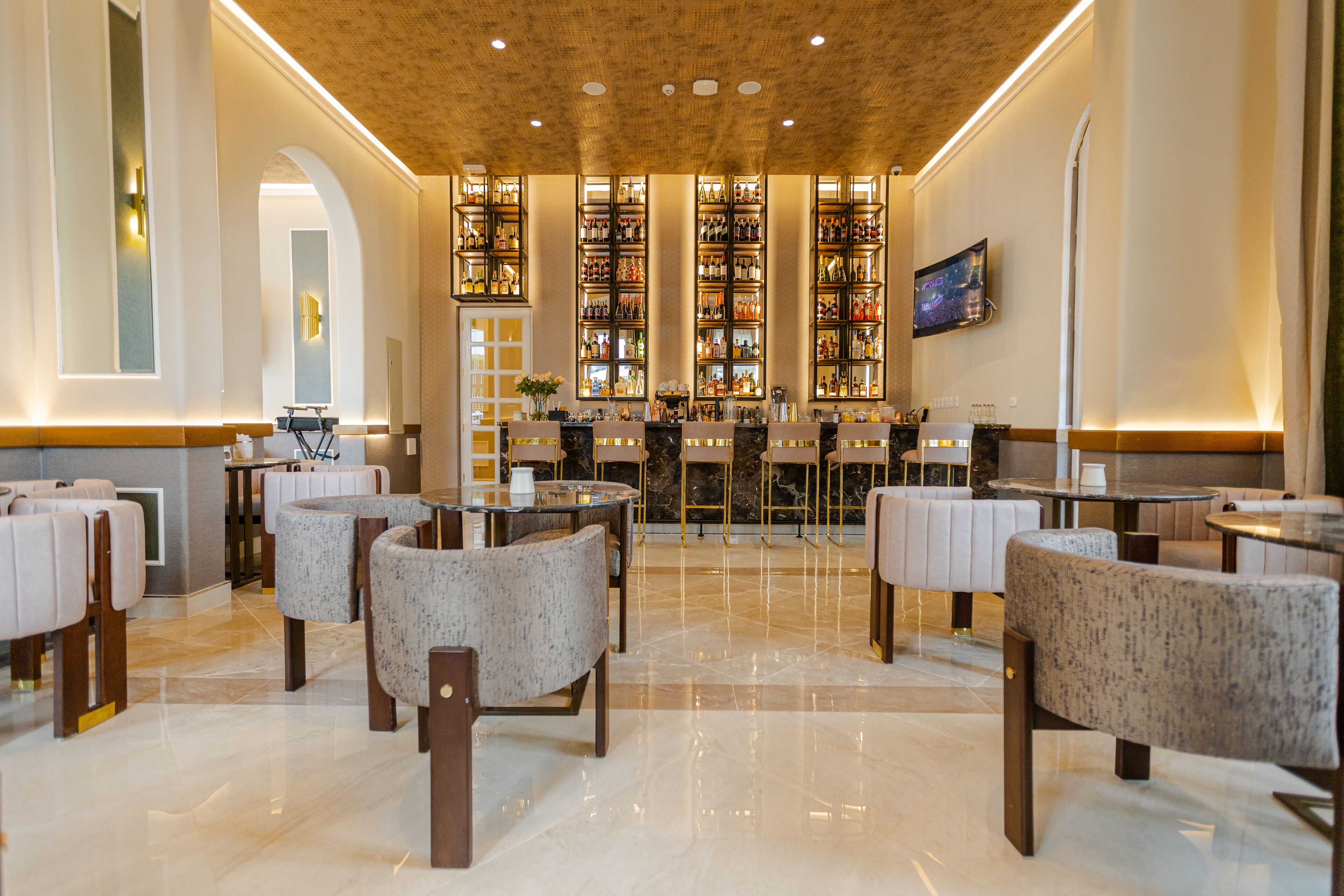 A hotel lobby with a bar area, seating, and a television screen.