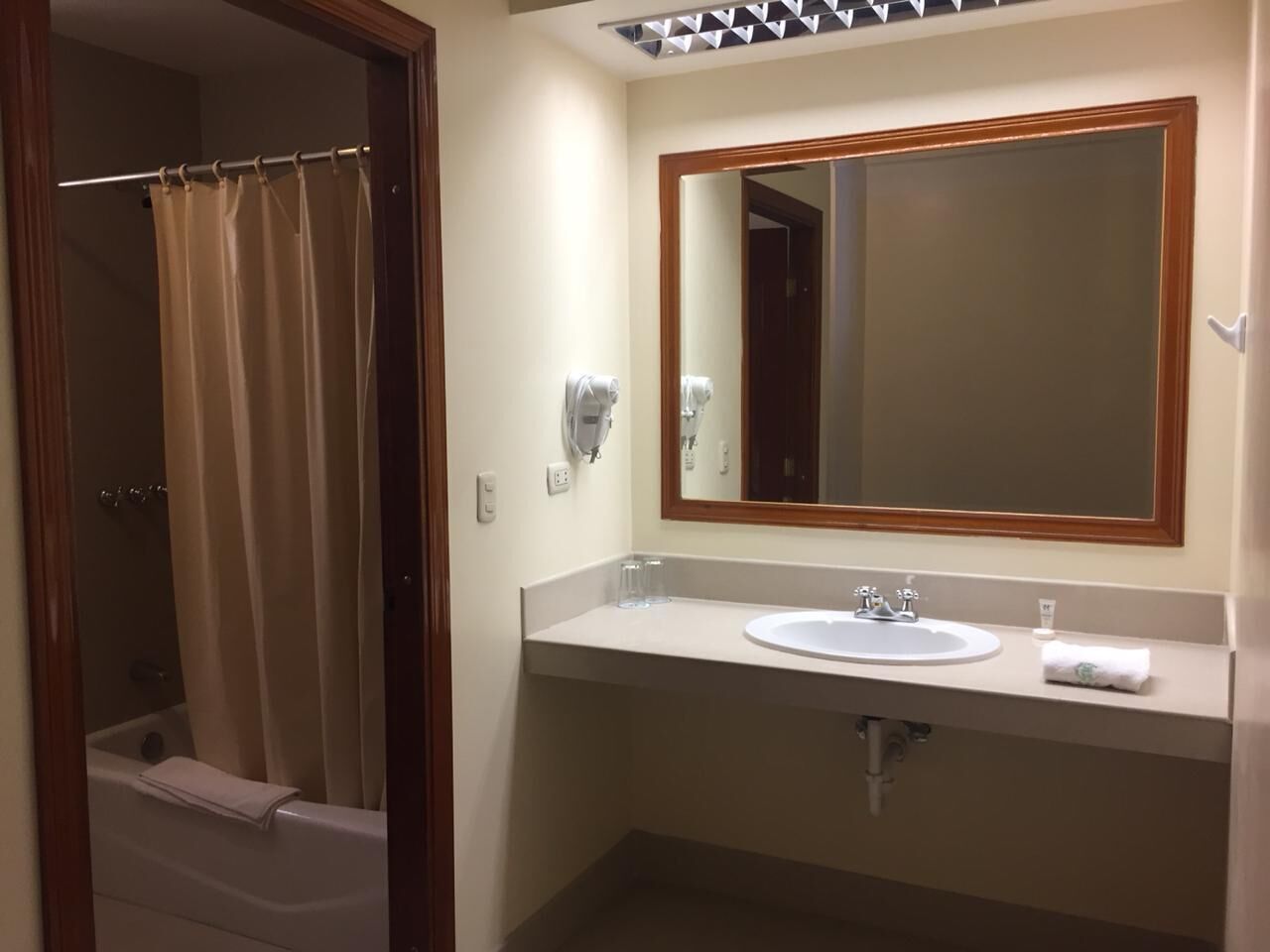 A bathroom with a bathtub, a sink, a mirror, and a towel rack.