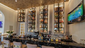 A bar area with multiple shelves of bottles, a TV screen, and bar stools. - Hotel de Turistas Huancayo - Hotel Asociado Casa Andina (Huancayo)
