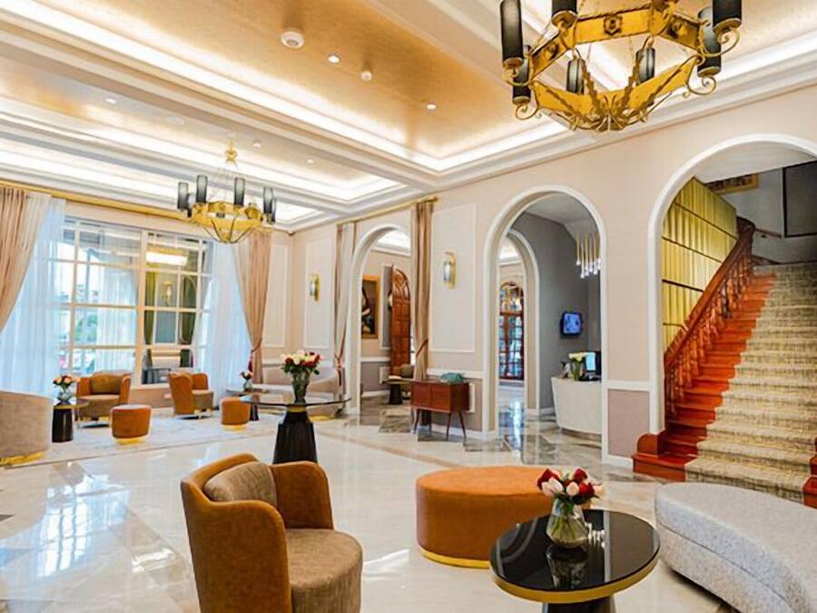 Eine geräumige Lobby mit einer imposanten Treppe, gemütlichen Sitzbereichen und einem Kronleuchter.