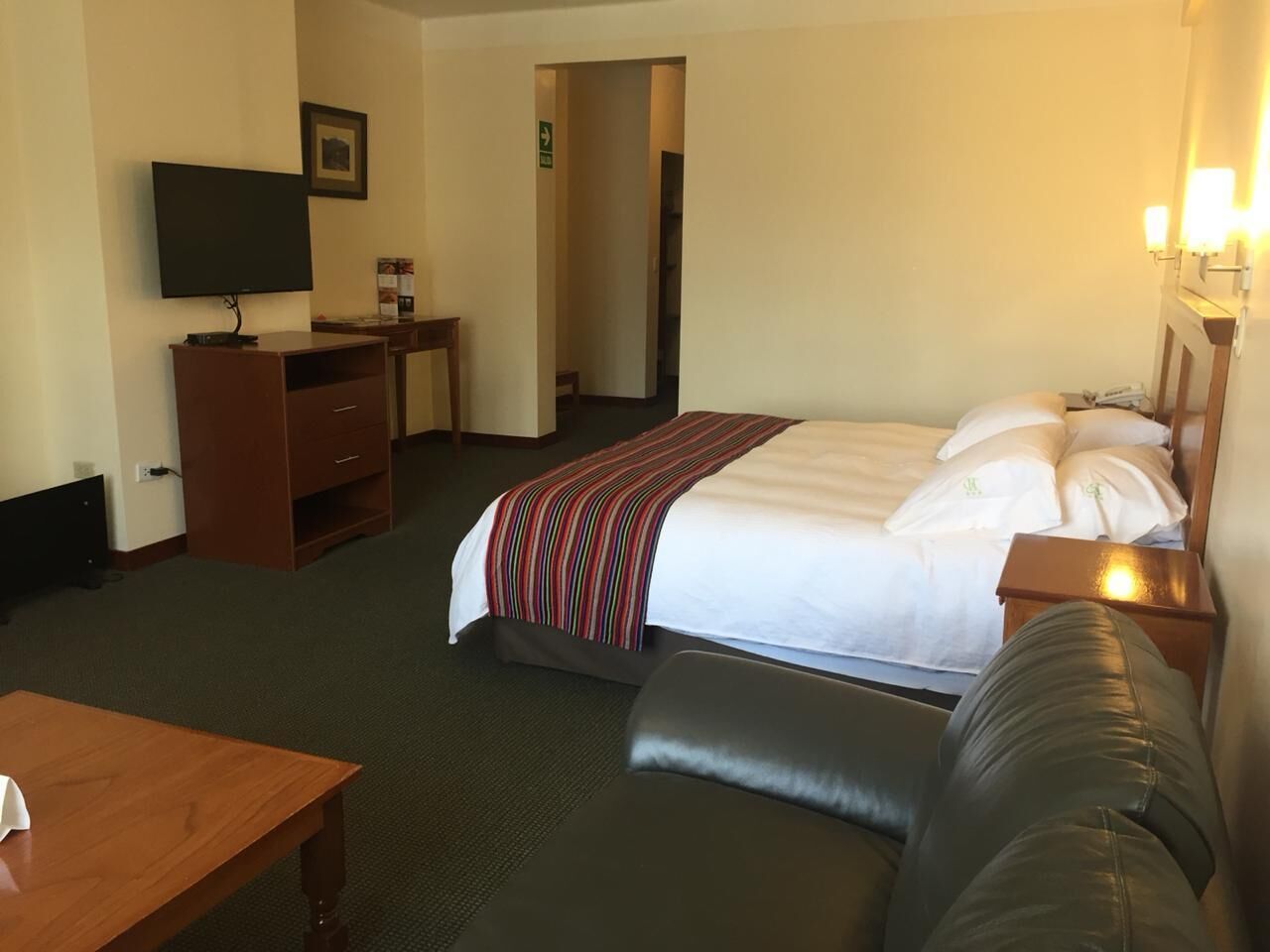 A hotel room with a bed, a desk, a television, and a couch.
