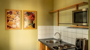 A kitchen with a sink, stove, and a television above it. There are two framed pictures on the wall. - Kipling by Interhome (Marianske Lazne)