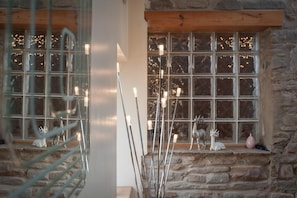 A stone wall with a window, decorative lights, and small animal figurines. - Beudy Bach (Llanelli)