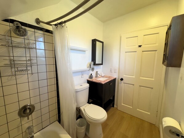 Baño con ducha, inodoro, lavamanos y una puerta.