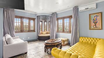 A spacious living room with a yellow sofa, a white armchair, and a round table.
