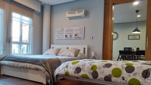 A bedroom with two beds, a wall-mounted air conditioner, a clock, and a desk with a chair. - ÁgoraLux, The door of Ourense. (Ourense)