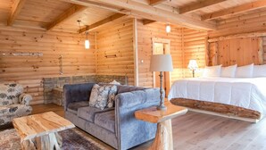A log cabin interior with a sofa, a bed, and a small table. - Cozy Lodge Fireplace Suite in Ohio's Amish Country (Millersburg)