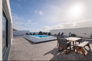 Un espace piscine aménagé sur le toit, comprenant une piscine, des chaises longues et une table avec des bancs.