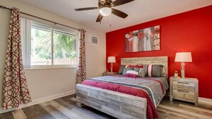 A bedroom with a wooden bed, two bedside tables, a ceiling fan, and a window with curtains. - 1BR with Private, Fenced Deck (Fort Lauderdale)