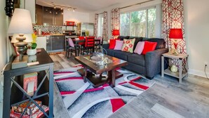 A modern living room with a sofa, coffee table, and dining area. - 1BR with Private, Fenced Deck (Fort Lauderdale)
