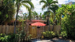 A wooden gate with a sign, surrounded by lush greenery and palm trees. - 1BR with Private, Fenced Deck (Fort Lauderdale)